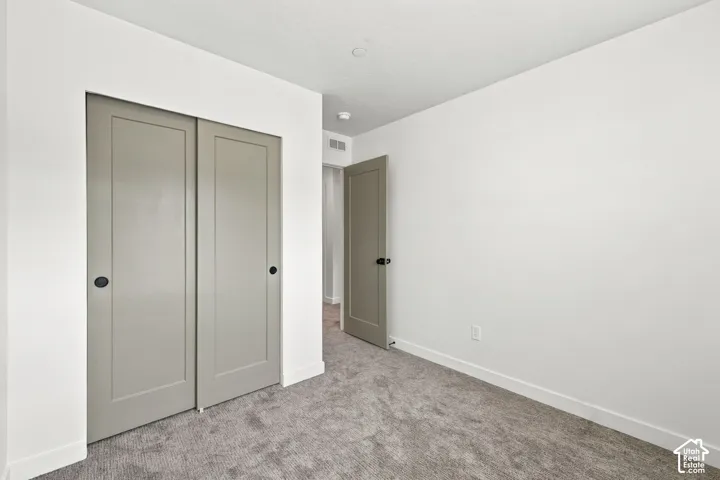 Neutral-toned carpet flooring, shaker-style closet doors, solid-core interior doors, and matte black hardware