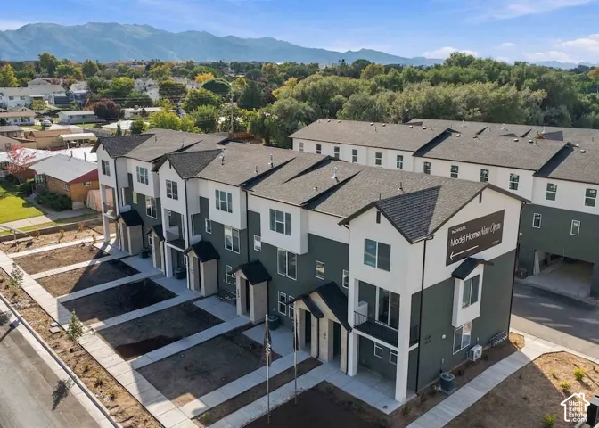 Multi-story townhome exterior featuring dual-tone siding, pitched shingle roofing, second-story balconies, and mountain scenery