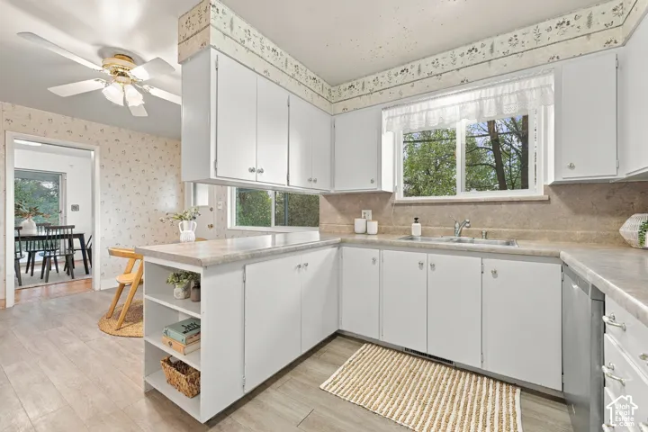 Kitchen featuring white cabinetry with open shelving, neutral-toned countertops, wood-finish flooring, a double-basin stainless steel sink, and a ceiling-mounted light fixture