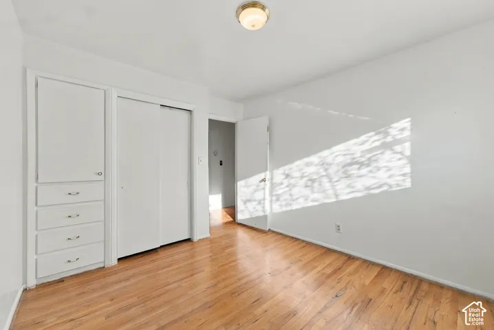 Wood-finish flooring, white walls, built-in cabinetry featuring four drawers and a vertical cabinet door, dual-panel sliding closet, and a flush-mount ceiling light fixture
