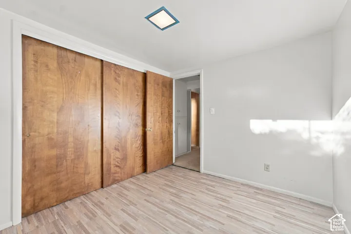 Room featuring wood-finish flooring, full-height sliding wood-grain closet doors, and recessed square ceiling lighting