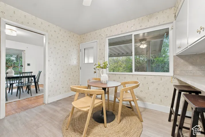 Eat-in area featuring wood-finish flooring, a white-framed sliding window, and a white exterior-grade door with a glass panel