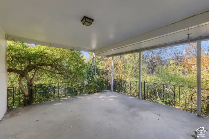 Covered concrete patio featuring ornate metal railings and overhead lighting