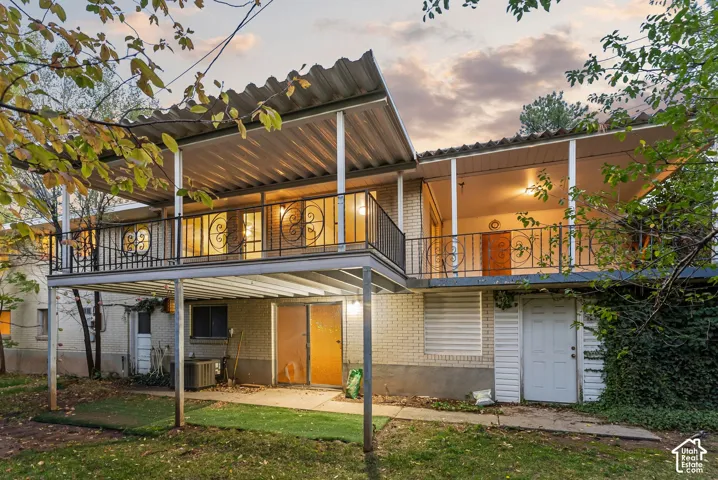 Walk out basement, a covered upper-level balcony with decorative wrought iron railings, and a concrete patio