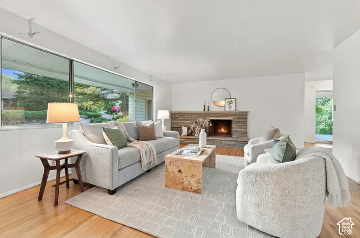 Living area featuring expansive picture windows, natural stone-faced fireplace, and wood-finish flooring