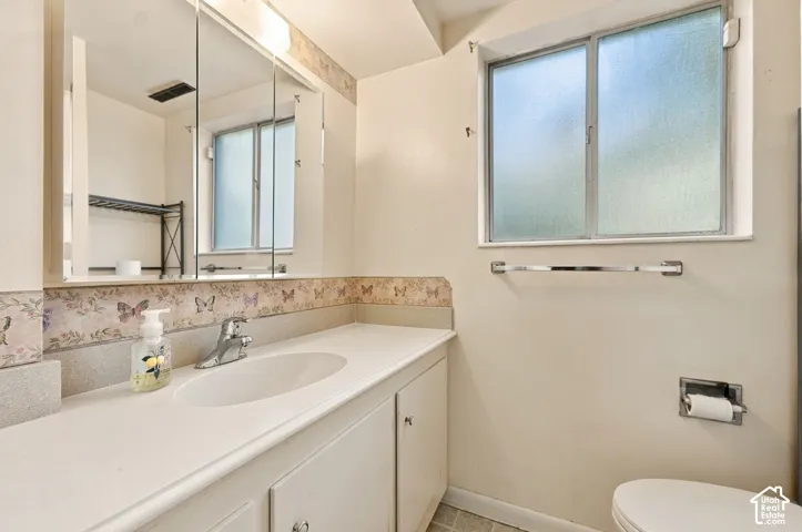 Bathroom featuring a vanity with a solid-surface countertop, an integrated sink basin, a multi-panel mirrored medicine cabinet, and a sliding privacy window