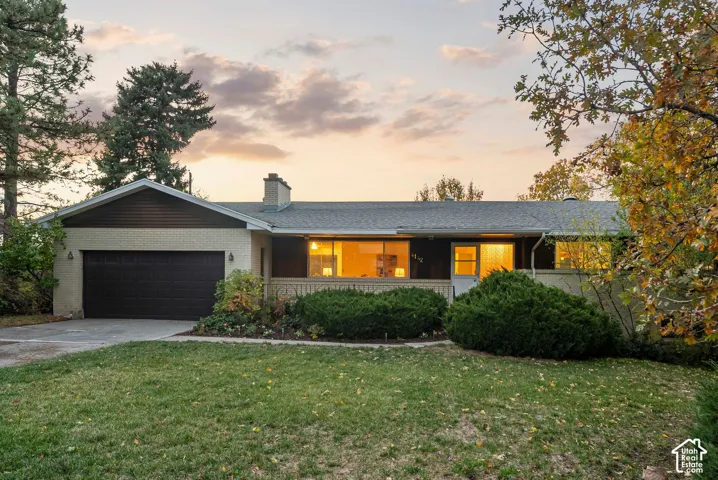Single-story residence featuring a brick and horizontal siding exterior, an attached two-car garage, an asphalt shingle roof, and a stone-accented chimney