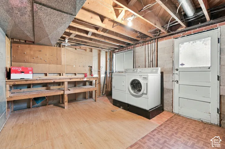 Utility area featuring a built-in wooden workbench with pegboard wall storage, exposed ceiling joists, concrete masonry walls, and a dedicated exterior access door
