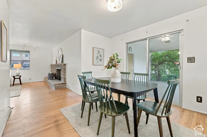 Dining area featuring wood-finish flooring, a stone-faced fireplace with a raised hearth, and a sliding glass door