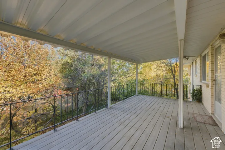 Covered deck featuring painted wood-finish decking, decorative wrought-iron railings, and a solid metal roof