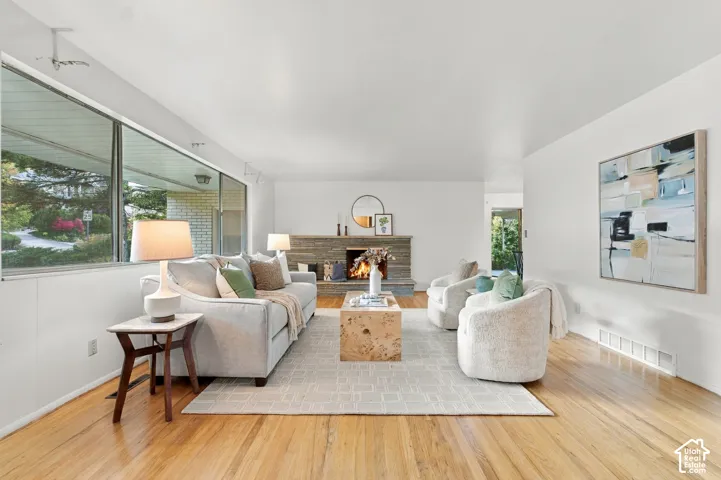 Living area featuring large-format horizontal windows, natural wood-finish flooring, and a floor-to-ceiling stone-clad fireplace