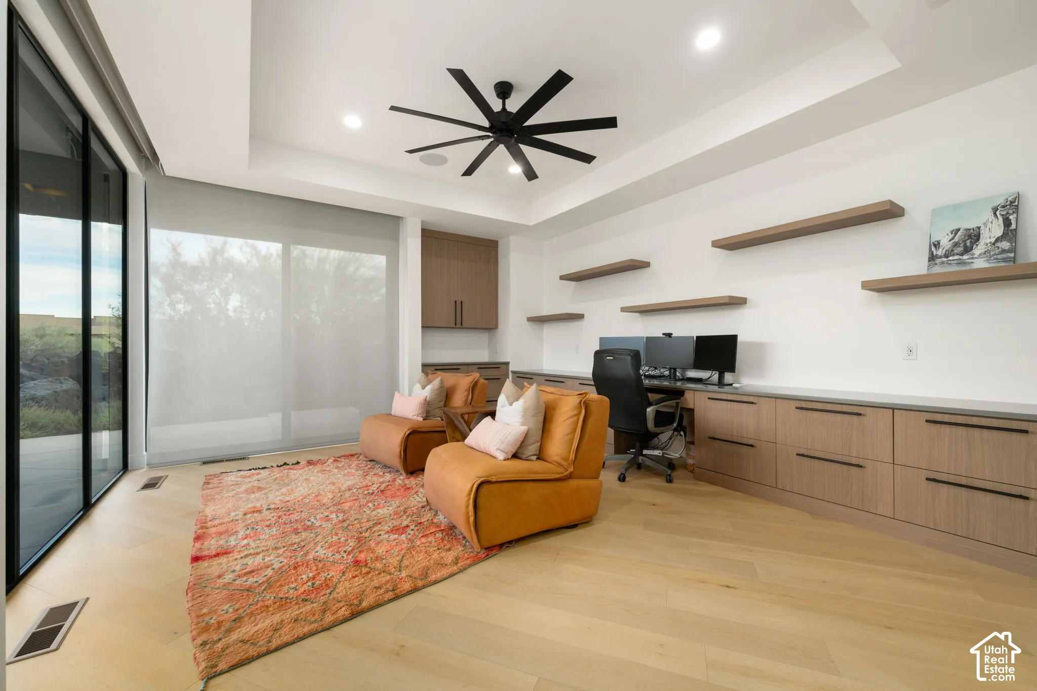 Custom office featuring wood-finish flooring, built-in cabinetry, floating wall shelves, a recessed ceiling, and floor-to-ceiling glass sliding doors