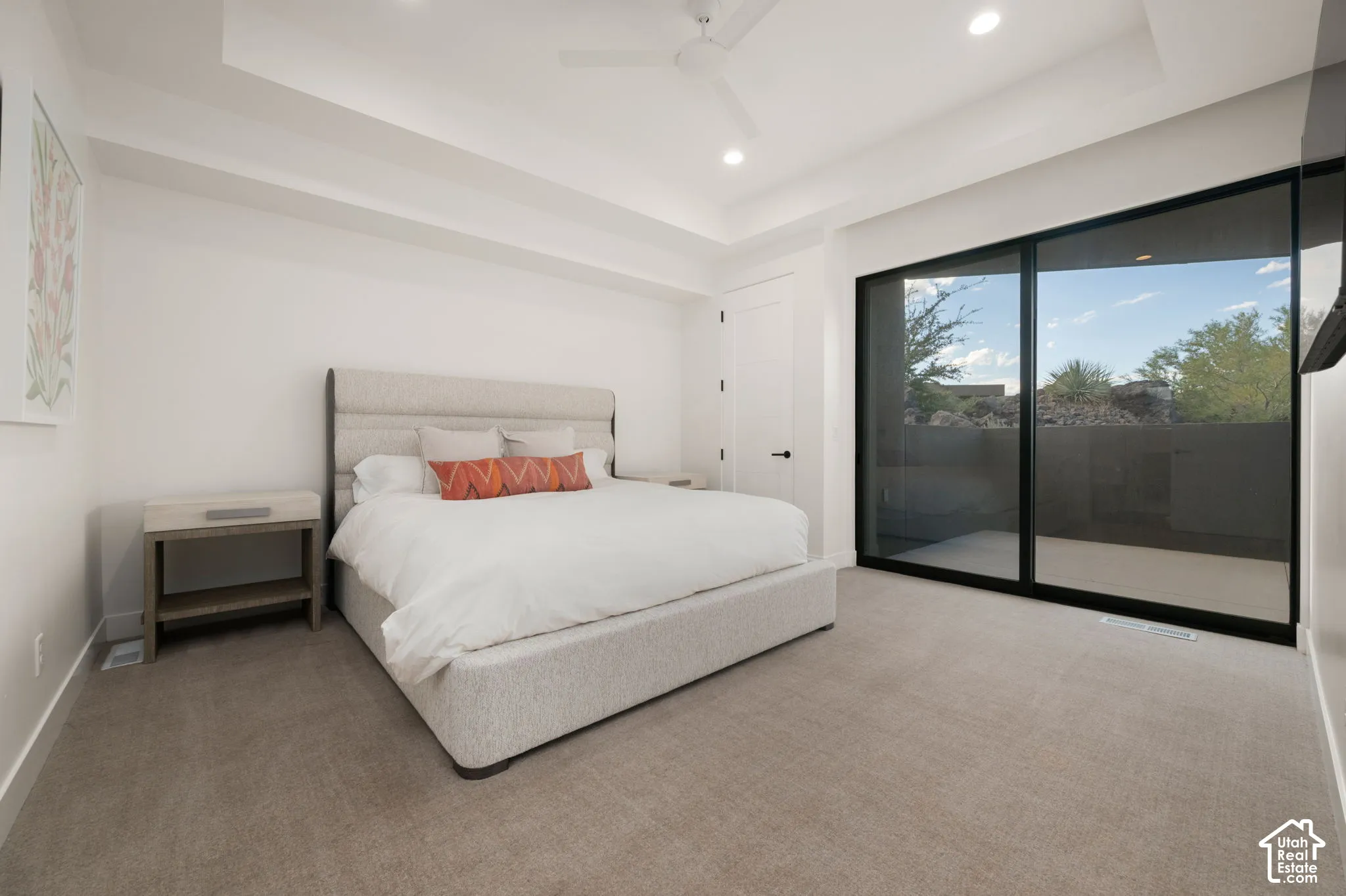 Tray ceiling with recessed lighting, large-format sliding glass door, neutral carpeting, and a ceiling fan