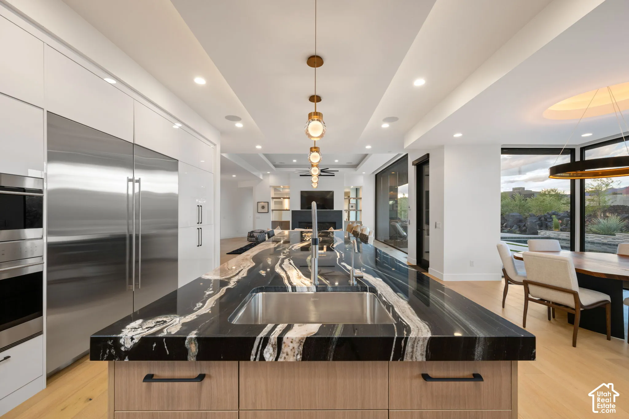 Kitchen featuring a large center island with a high-contrast natural stone countertop, integrated stainless steel appliances, recessed ceiling lighting, and wood-finish flooring