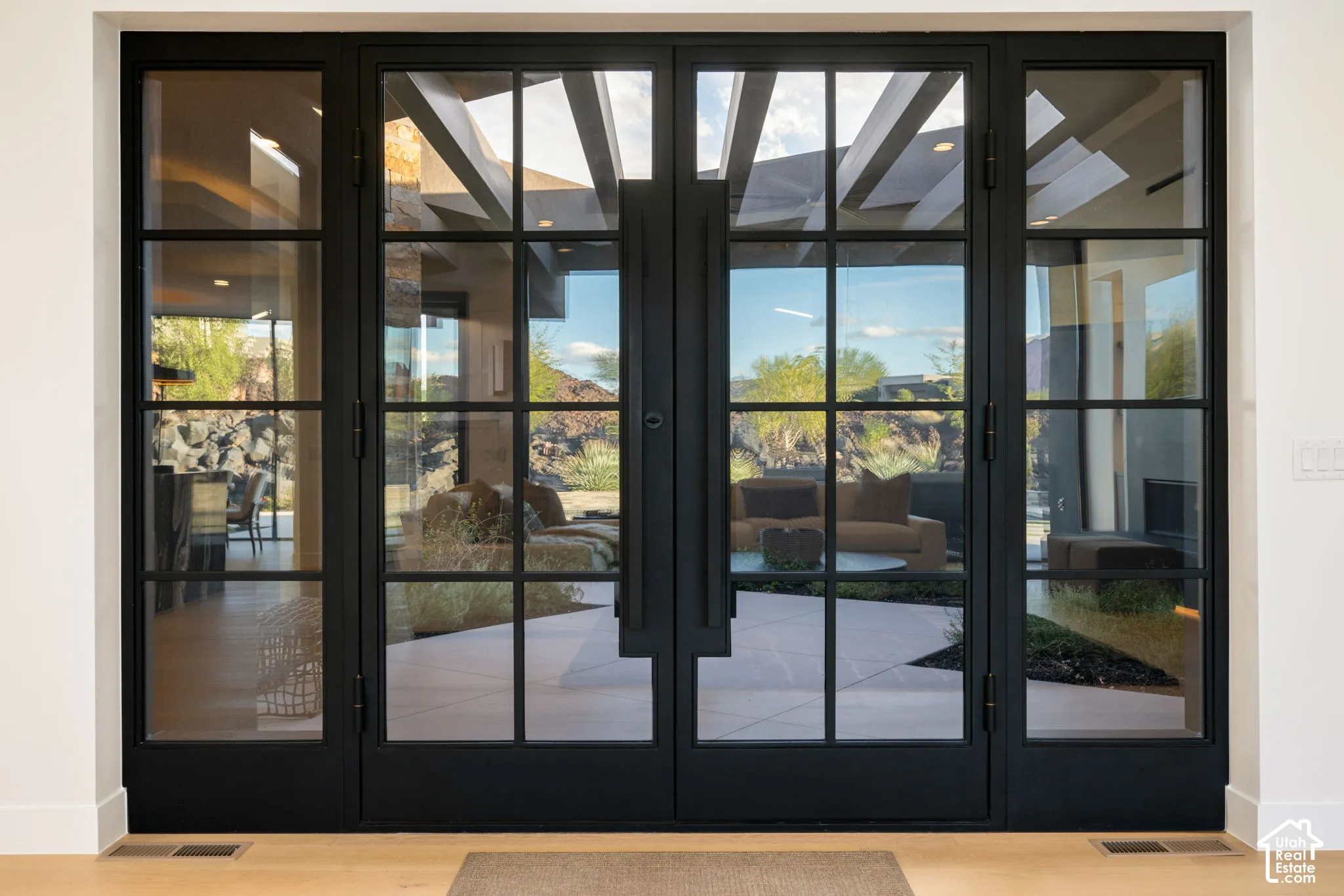 Black metal-framed double glass doors with multi-lite panes and elongated vertical handles