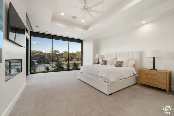 Floor-to-ceiling windows, recessed tray ceiling, built-in linear fireplace, and integrated ceiling fan