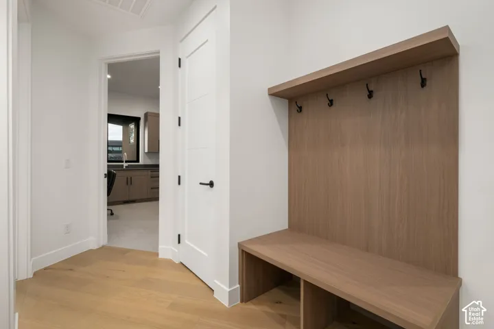 Built-in wood-finish drop zone featuring a bench with lower storage compartments, integrated shelving, and matte black hardware