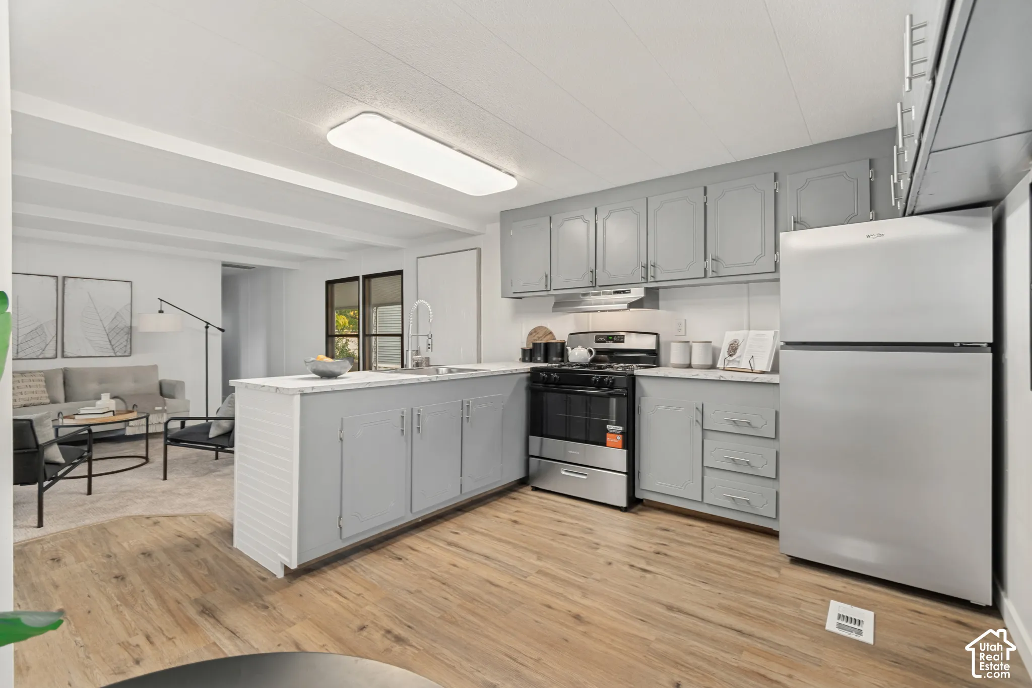 Kitchen featuring light grey cabinetry, stone-patterned countertops, stainless steel appliances, and wood-finish flooring