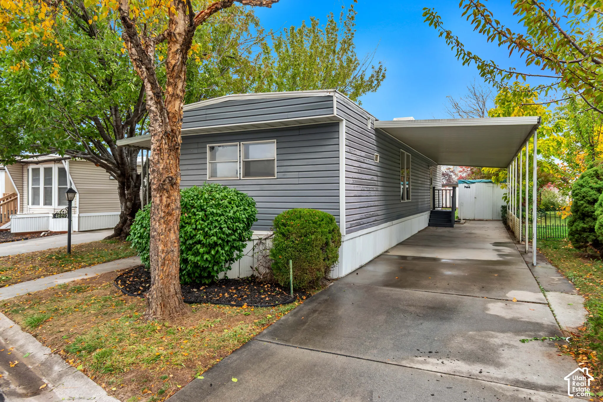 Exterior featuring horizontal siding, a concrete carport with metal roofing, and mature landscaping