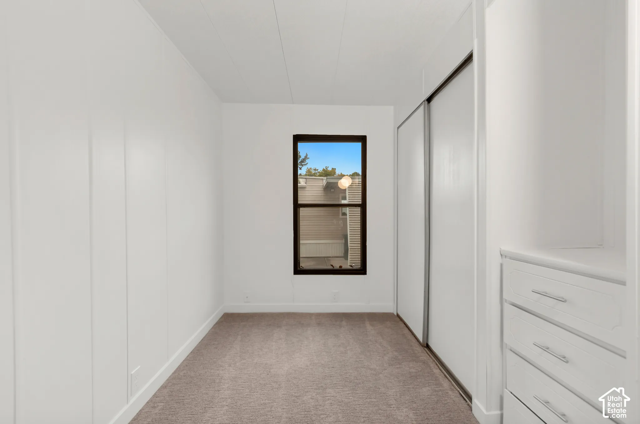 Neutral wall paneling, carpeting, sliding closet doors, and built-in dresser storage