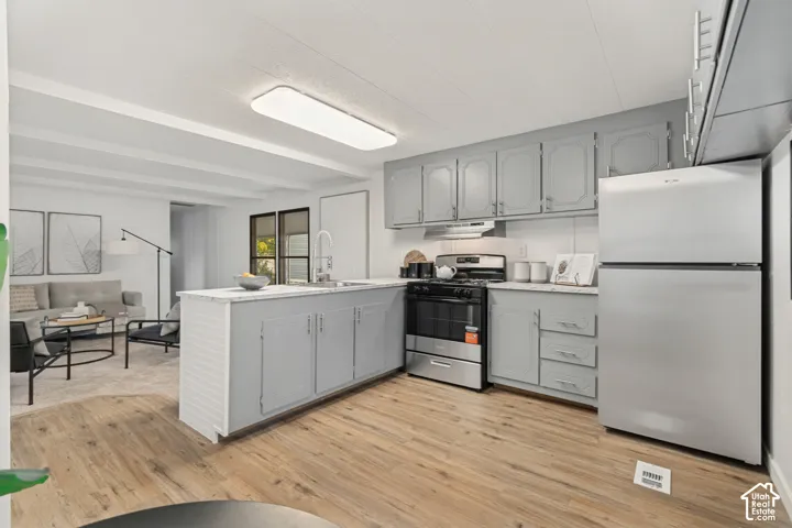 Kitchen featuring light grey cabinetry, stone-patterned countertops, stainless steel appliances, and wood-finish flooring