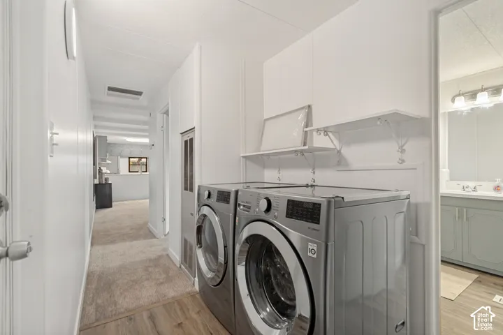 Laundry area featuring white built-in upper cabinetry and open shelving, neutral-toned carpeting, and a wall-mounted heater