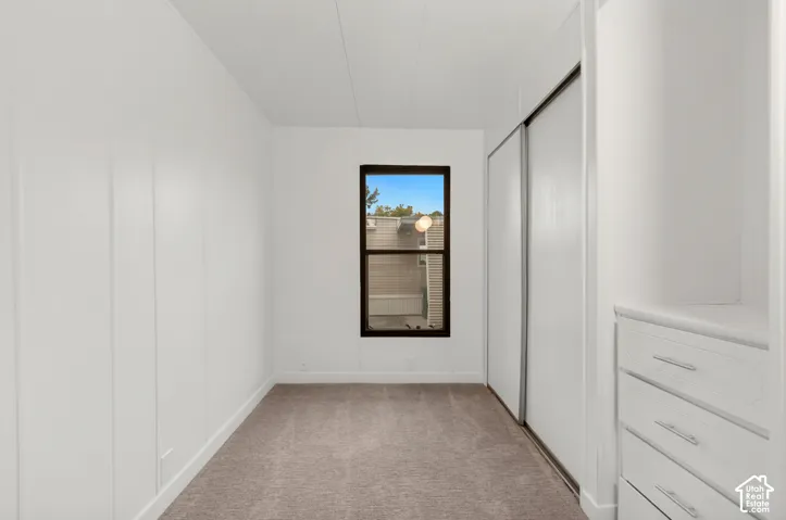 Neutral wall paneling, carpeting, sliding closet doors, and built-in dresser storage