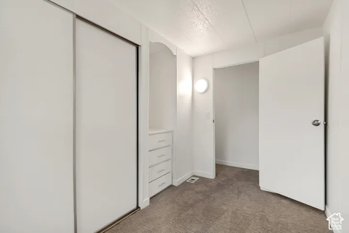Sliding-door closet featuring built-in cabinetry with four integrated drawers and neutral wall-to-wall carpeting