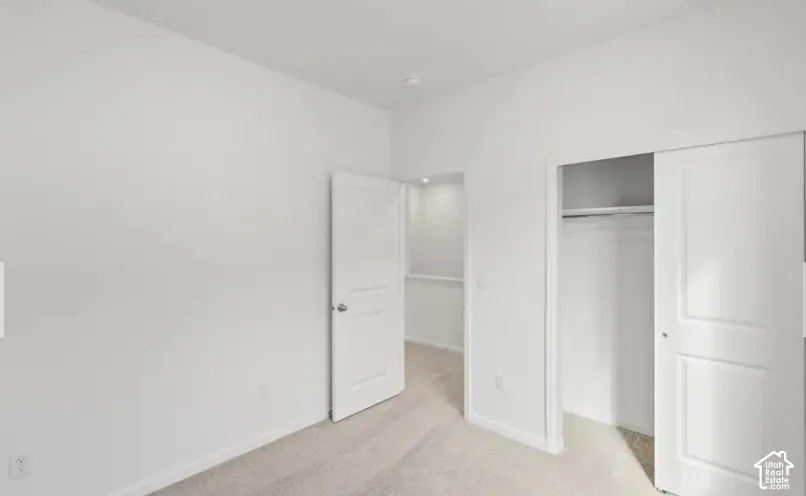 Neutral-toned carpeting, white walls, two-panel interior doors, and a built-in closet with overhead shelving