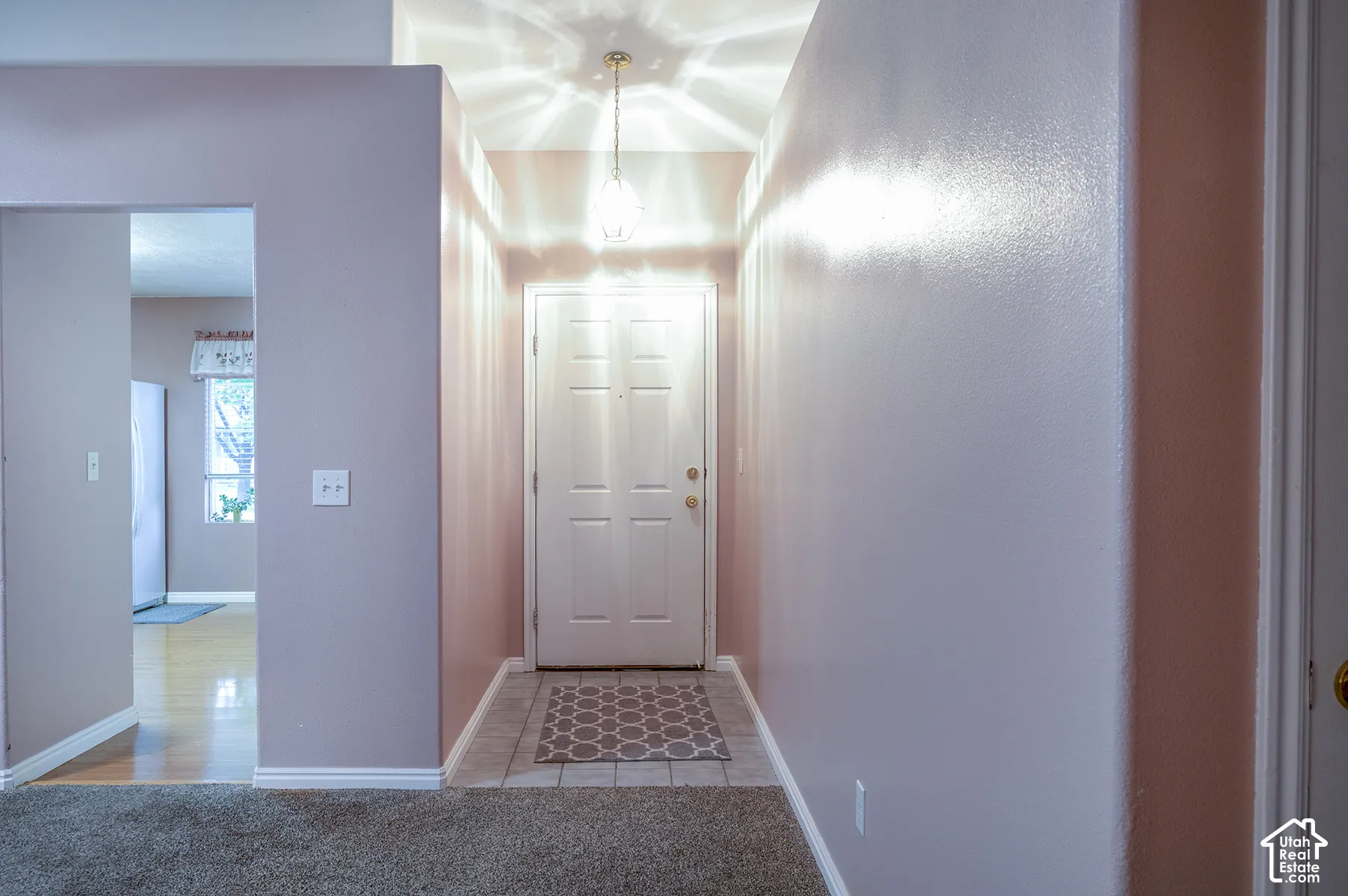 Entryway featuring high ceilings, a multi-panel door, tile flooring, and a pendant light fixture