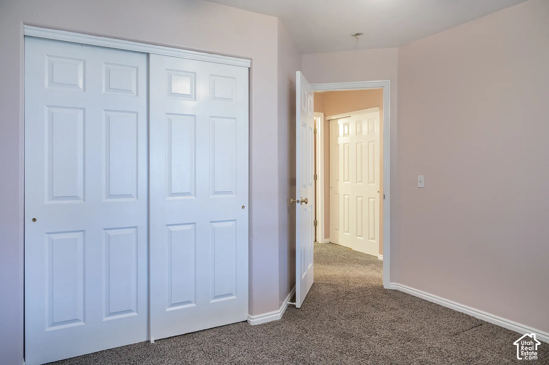 Interior space featuring neutral wall paint, carpeted flooring, and white paneled sliding closet doors