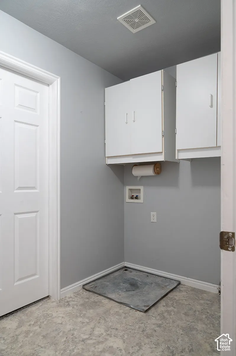 Utility area featuring white built-in wall cabinetry, neutral wall paint, and resilient sheet flooring