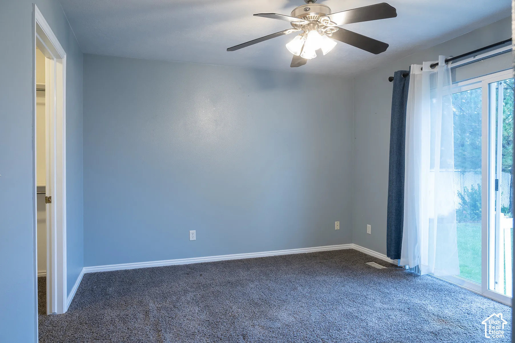 Room featuring neutral wall-to-wall carpeting, ceiling fan with integrated lighting, and sliding glass doors with exterior access