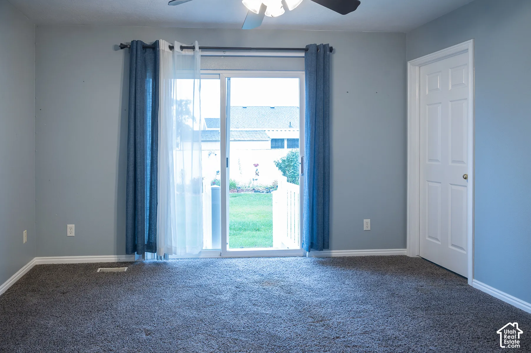 Room featuring carpeted flooring, a six-panel door, and a sliding glass door providing access to the exterior