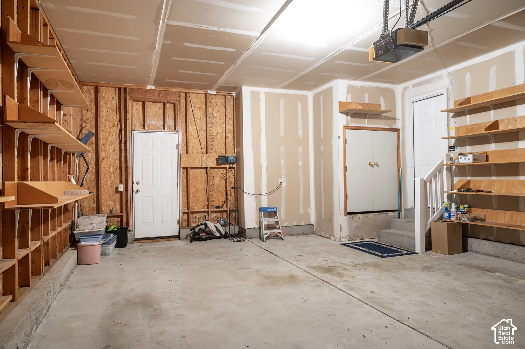 Garage space featuring concrete flooring, built-in wooden shelving units, integrated storage cabinetry, and two exterior access doors
