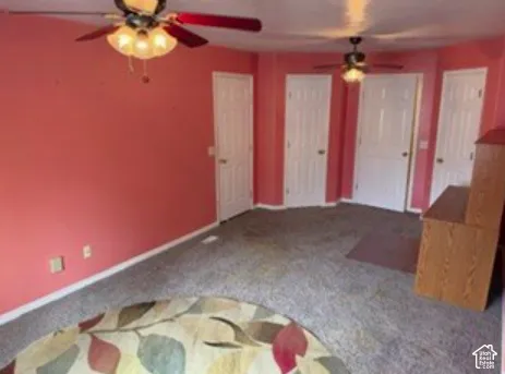 Interior room featuring wall-to-wall carpeting, two ceiling fans with multi-bulb light fixtures, and multiple interior doors with six-panel detailing