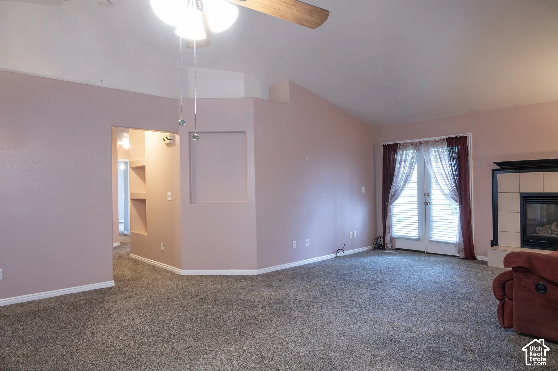 Vaulted ceilings, a built-in architectural niche, a fireplace with tiled surround, and glass-paneled double doors
