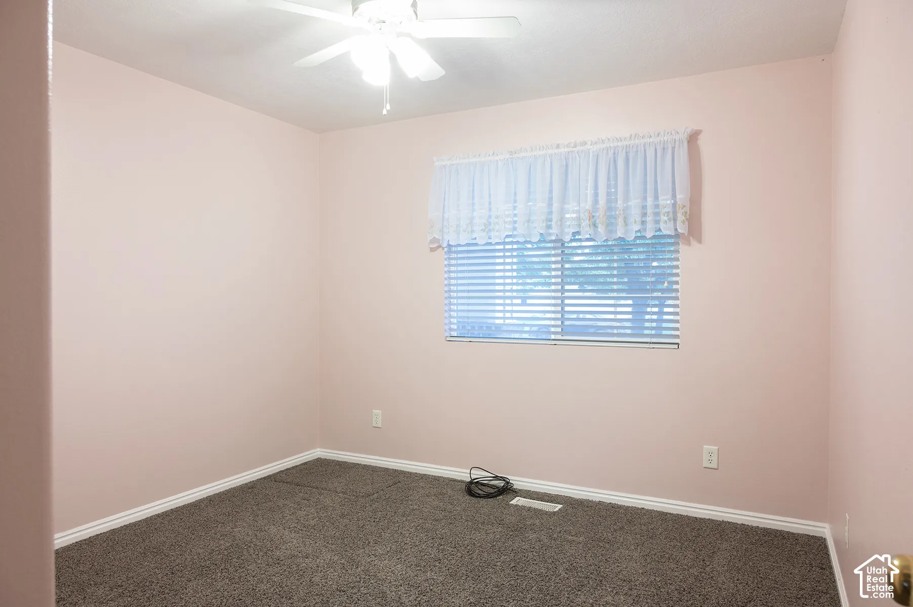 Neutral-toned carpet flooring, ceiling-mounted light fixture with integrated fan, and horizontal window blinds