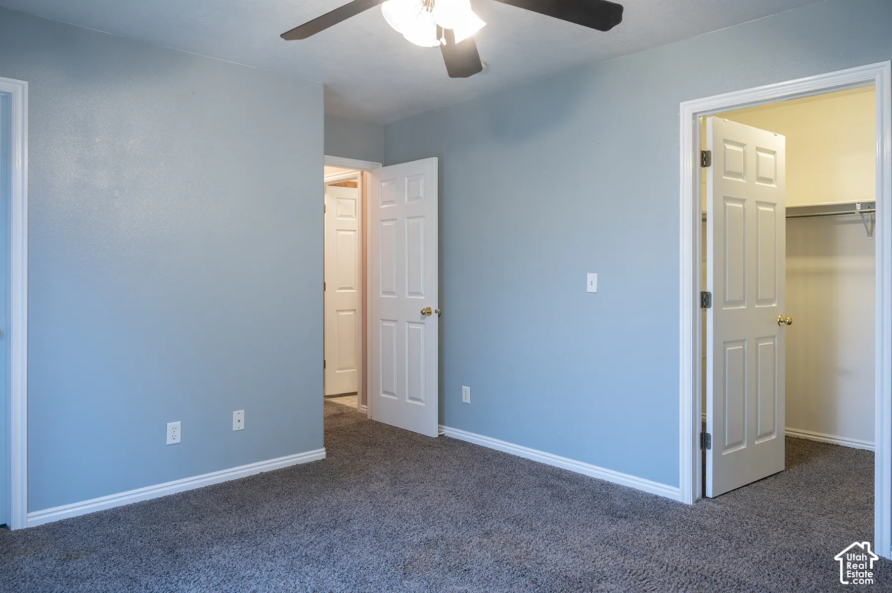 Room featuring neutral-toned carpeting, six-panel interior doors, and a ceiling-mounted light fixture with an integrated fan