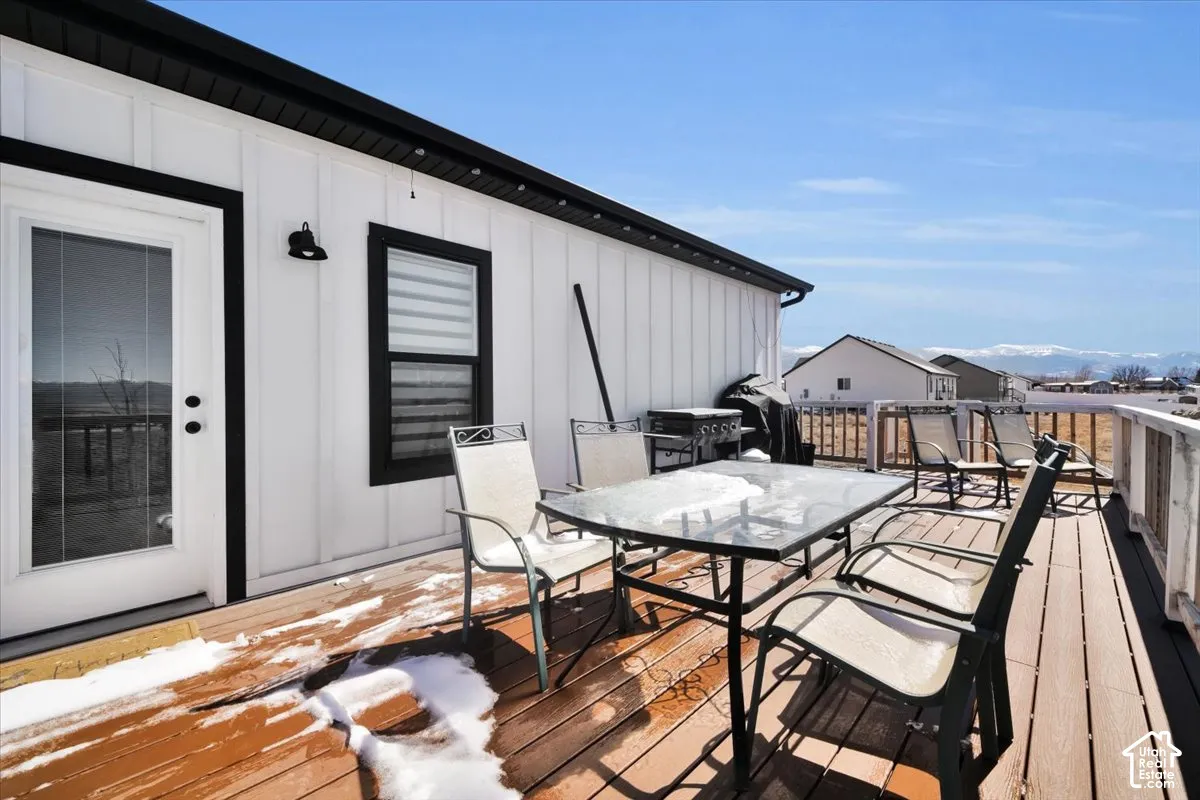 Elevated composite deck featuring white board-and-batten exterior siding, contrasting dark window and door trim, and mountain range scenery