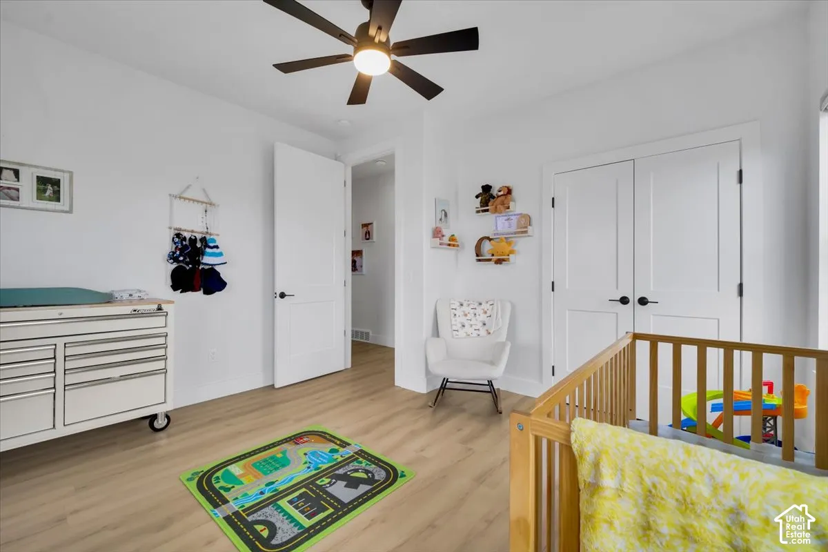 Light-toned wood-finish flooring, ceiling fan with integrated lighting, and white shaker-style interior doors with matte black hardware