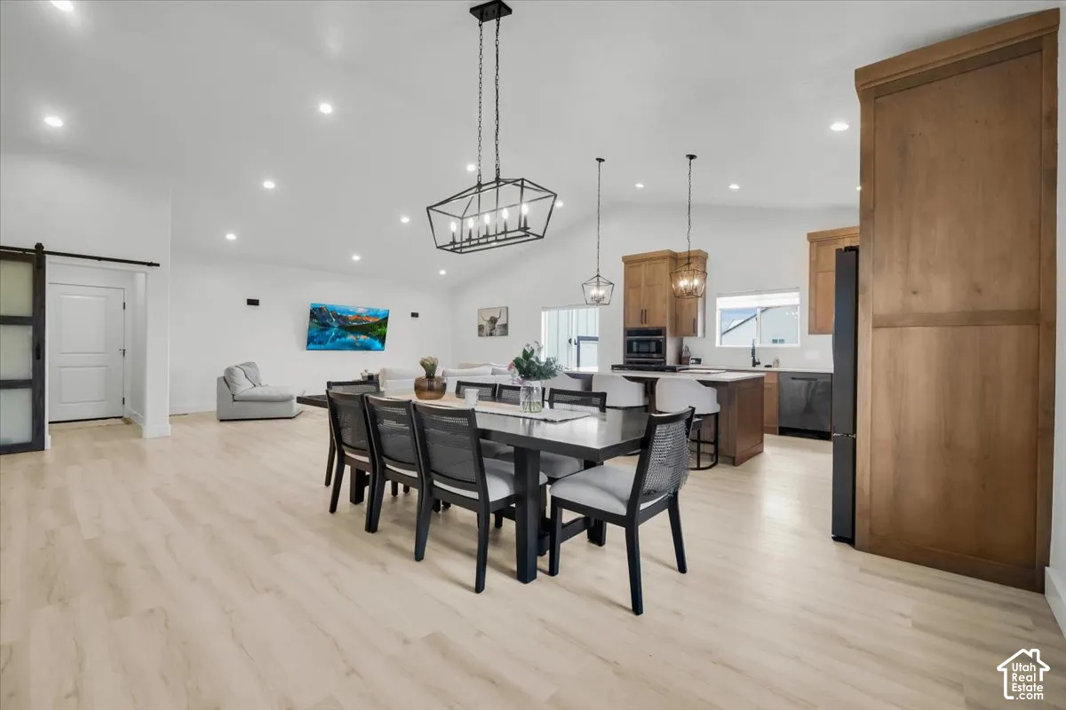 Open-concept interior featuring vaulted ceilings, wood-finish flooring, custom wood cabinetry, a central kitchen island, and geometric statement lighting
