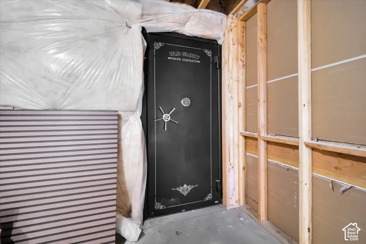 Built-in black metal vault door featuring a mechanical dial and wheel handle, framed by unfinished wood studs and exposed wall insulation