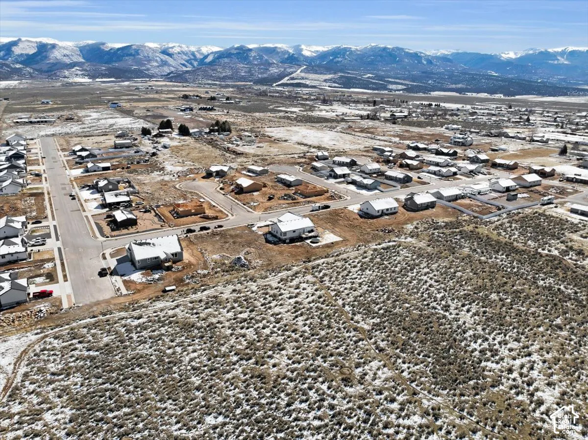 Aerial perspective featuring expansive undeveloped acreage with native high-desert vegetation and prominent mountain range scenery