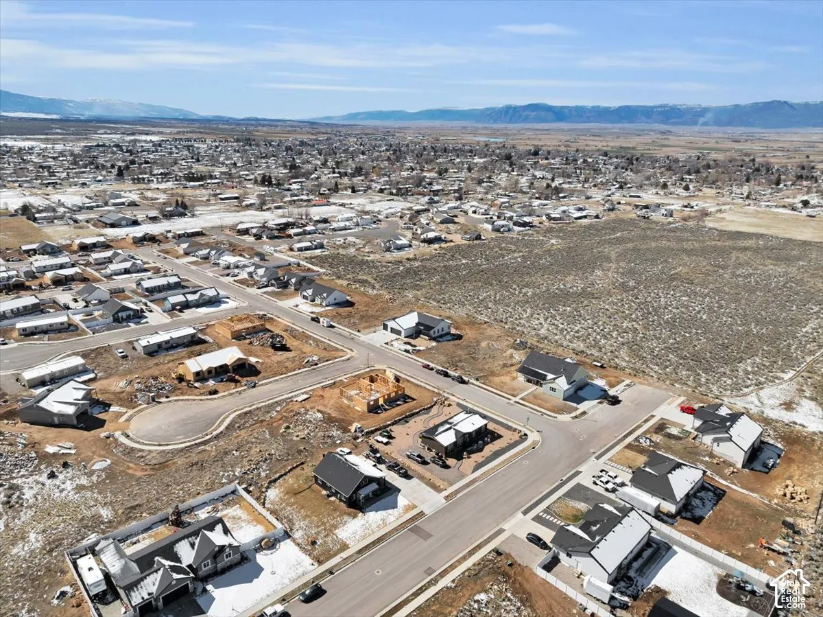 Aerial perspective of a residential development featuring paved street infrastructure and mountain range backdrop