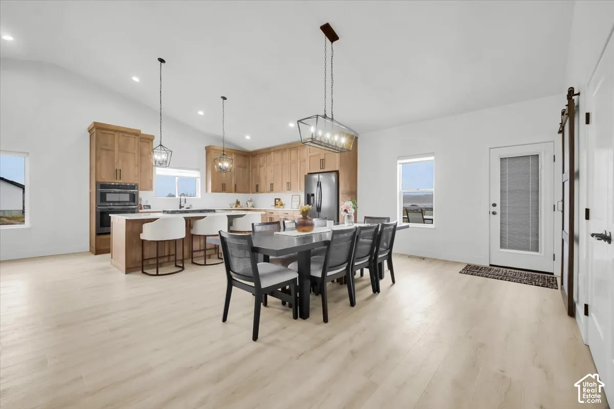Open-concept area featuring vaulted ceilings, wood-finish flooring, wood cabinetry, stone countertops, and recessed lighting