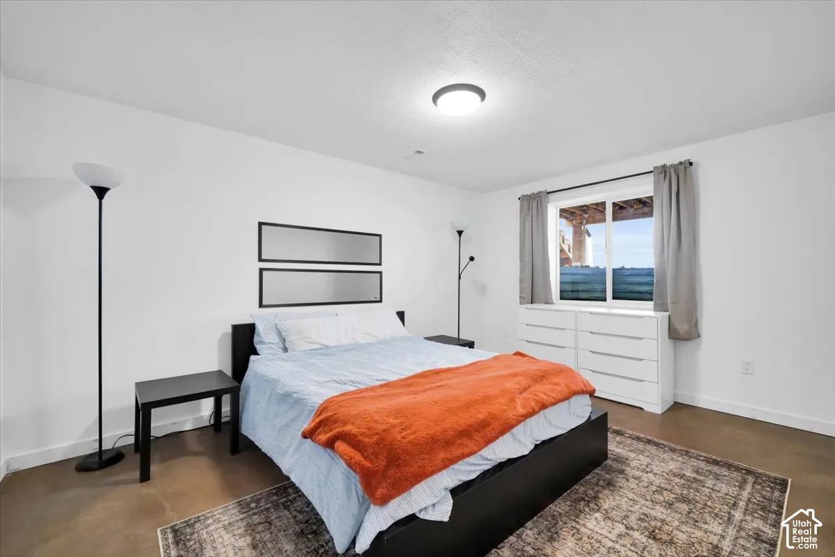 Spacious interior featuring neutral wall tones, low-maintenance concrete flooring, and a large horizontal sliding window with natural light