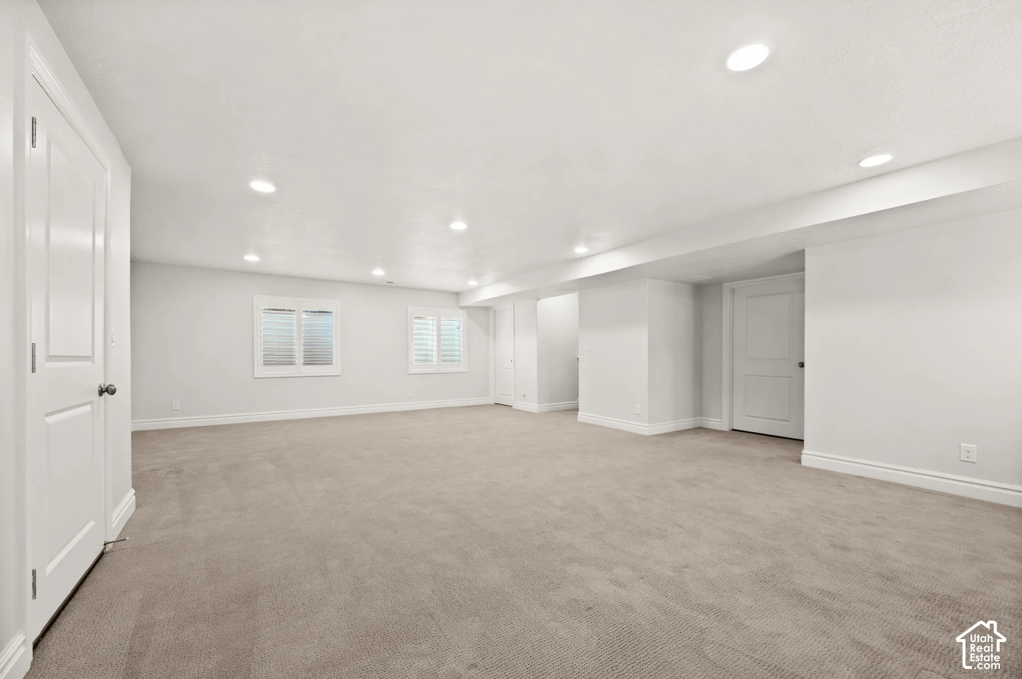 Neutral-toned room featuring wall-to-wall carpeting, recessed ceiling lighting, and windows finished with plantation shutters