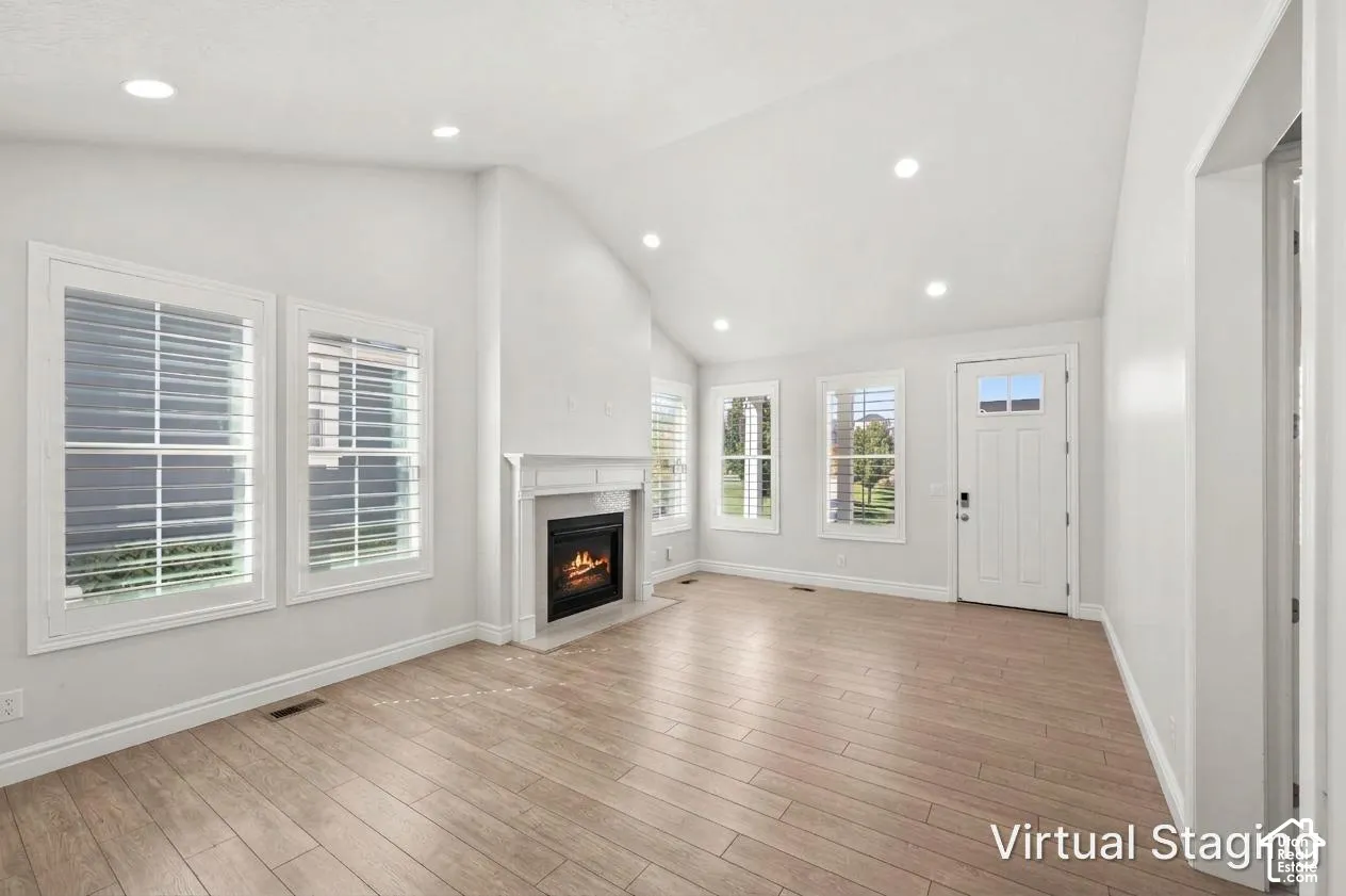 Vaulted ceilings, wood-finish flooring, recessed lighting, and a fireplace with a decorative mantel