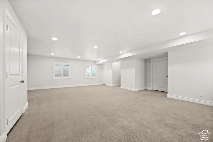 Neutral-toned room featuring wall-to-wall carpeting, recessed ceiling lighting, and windows finished with plantation shutters